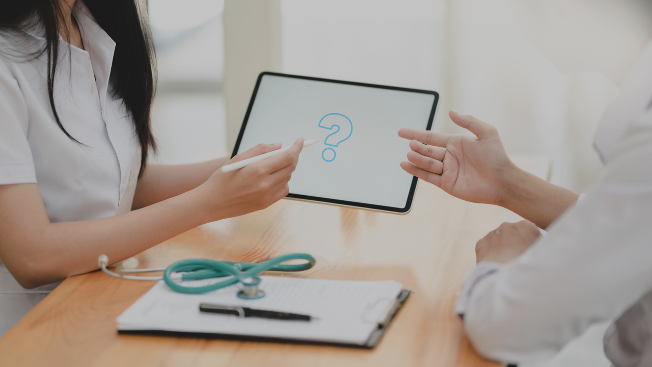 Profissionais da saúde conversando em frente a um tablet. Imagem simboliza a dúvida: “como evitar as glosas médicas e hospitalares?”.