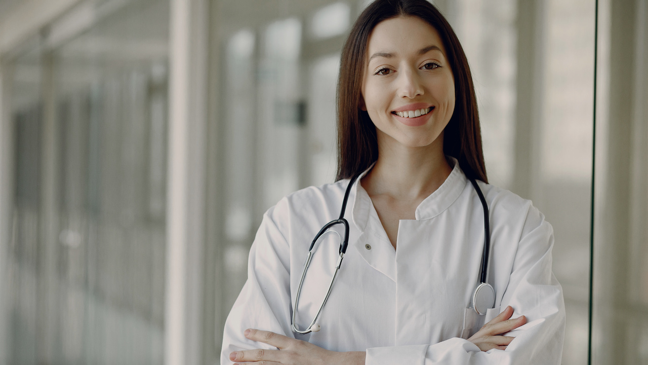 Médica sorrindo. Imagem simboliza profissional feliz por conseguir definir o preço das consultas.