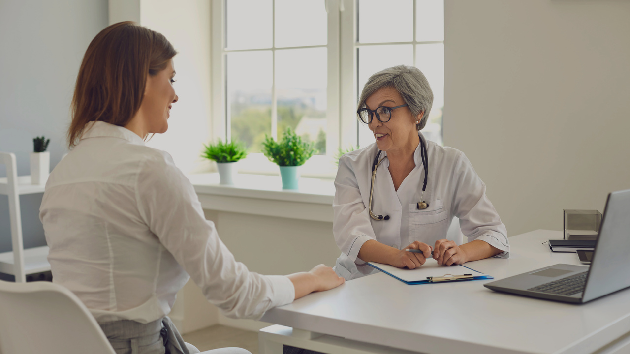 Médica conversando com paciente. Imagem remete à organização de consultório médico.