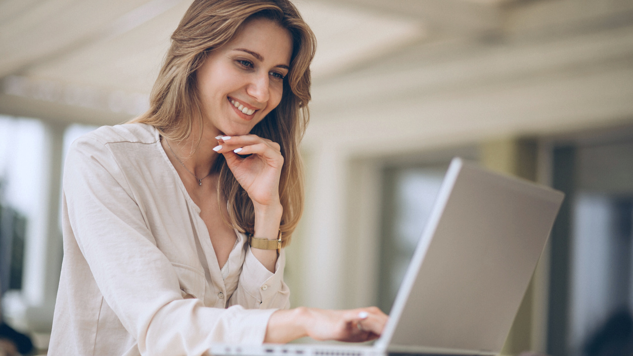 Profissional sorrindo em frente ao computador. Imagem simboliza profissional mexendo na área do cliente do Validador TISS.