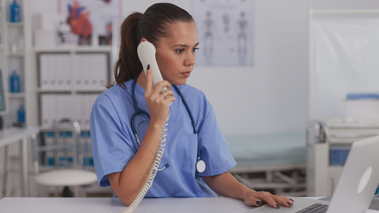 Médica atendendo chamada telefônica. Imagem simboliza que a profissional optou pela terceirização do faturamento e está conversando com o fornecedor.