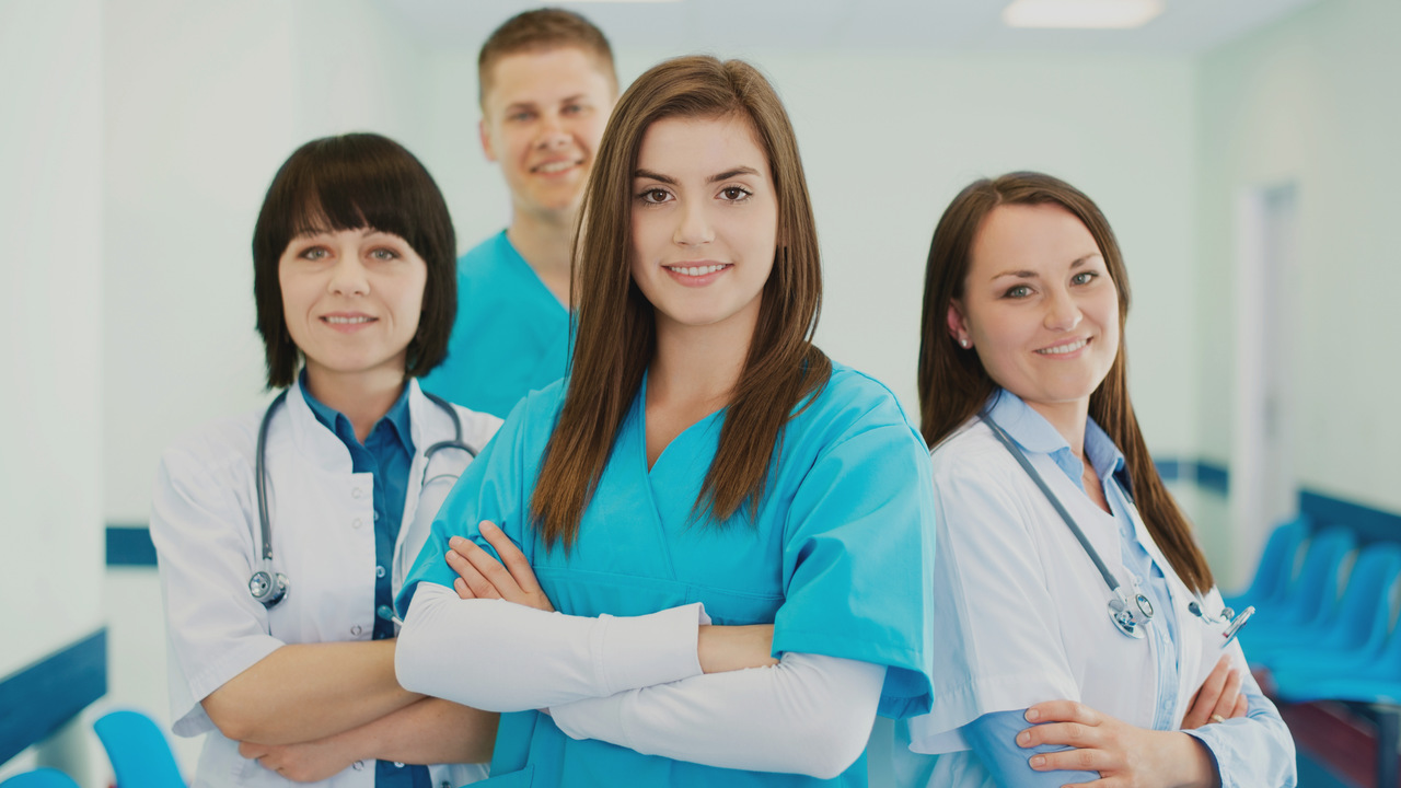 Equipe médica de 4 pessoas sorrindo. Imagem simboliza uma equipe médica empenhada.