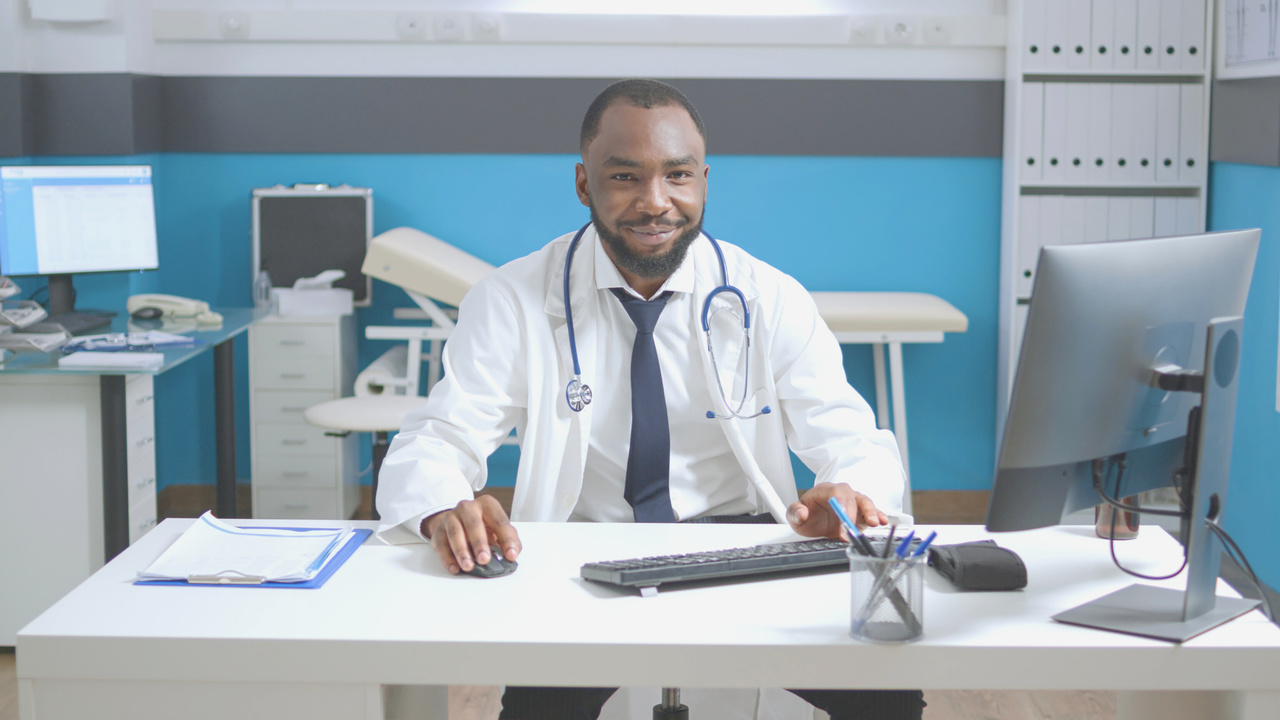 Médico sentado em seu escritório. Imagem simboliza que ele está preenchendo a guia de honorários.