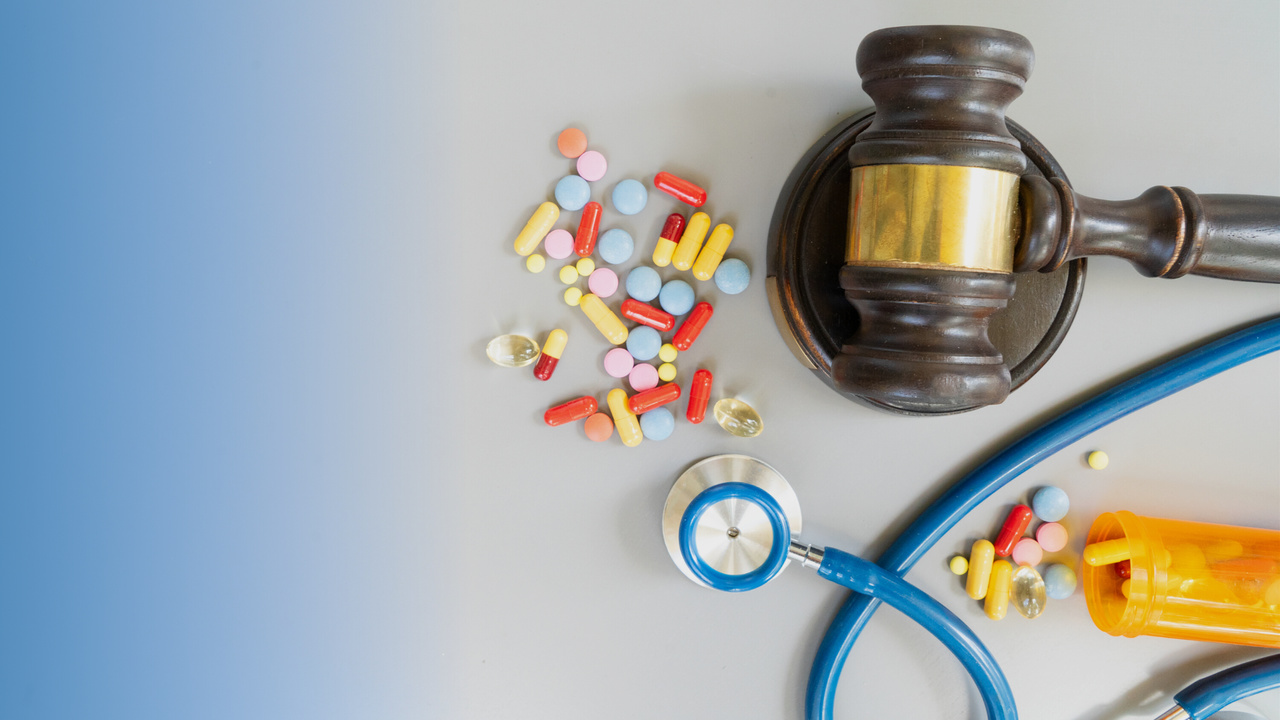 Martelo de juiz e remédios na mesa. Imagem simboliza a legislação de saúde suplementar no Brasil.