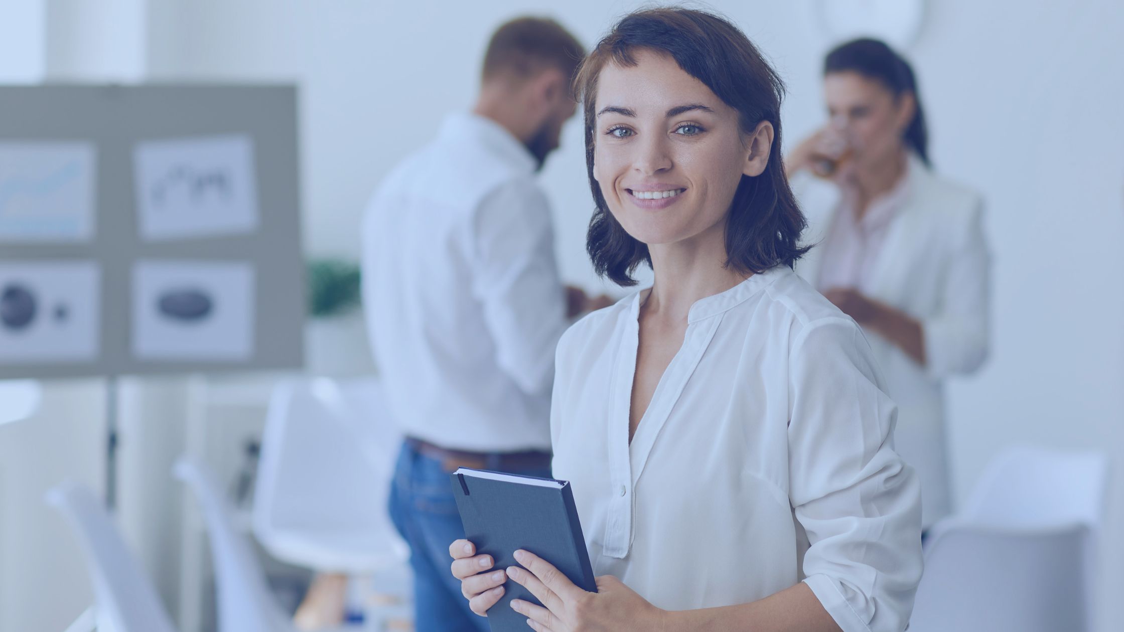 Mulher segurando caderno e sorrindo. Imagem simboliza que ela está anotando as regras da versão TISS 04.01.00.