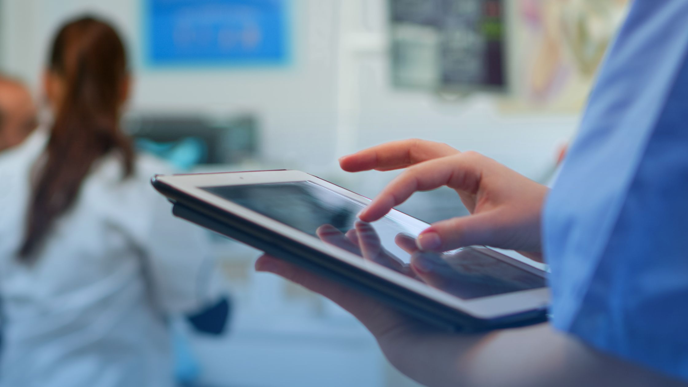 Mulher segurando um tablet dentro de um hospital. A imagem representa a transformação na gestão hospitalar gerada pela tecnologia.